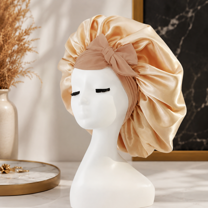 Luxuriöse Satin-Schlafhaube in elegantem Champagner mit dekorativer Schleife. Das glatte, seidige Material schützt das Haar während der Nacht, reduziert Reibung und hilft, Frizz sowie Haarbruch zu minimieren.