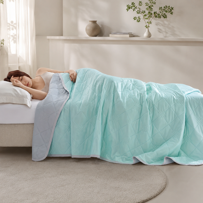 Wendbare kühlende Sommerdecke in Mint und Grau auf einem modernen Bett in einer stilvollen Schlafzimmerumgebung.